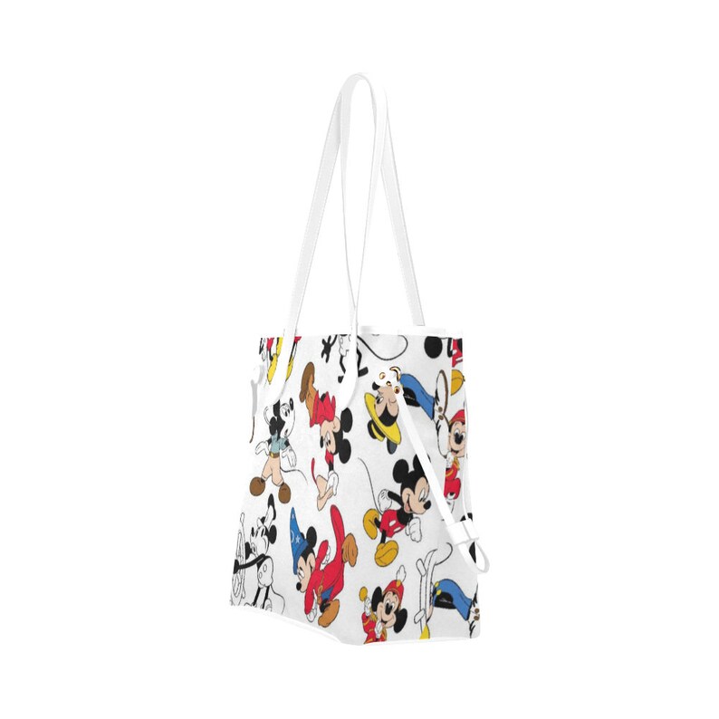 Puede incluir: Bolsa de tela blanca con un estampado colorido de Mickey Mouse y sus amigos. La bolsa tiene dos asas blancas.