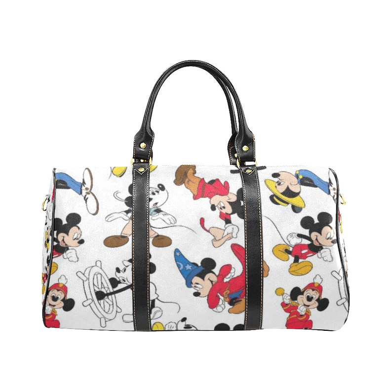 Puede incluir: Una bolsa de viaje blanca con un patr&oacute;n repetido de Mickey Mouse en varias poses. La bolsa tiene asas y ribetes de cuero negro, con herrajes dorados. La bolsa est&aacute; dise&ntilde;ada para viajar.
