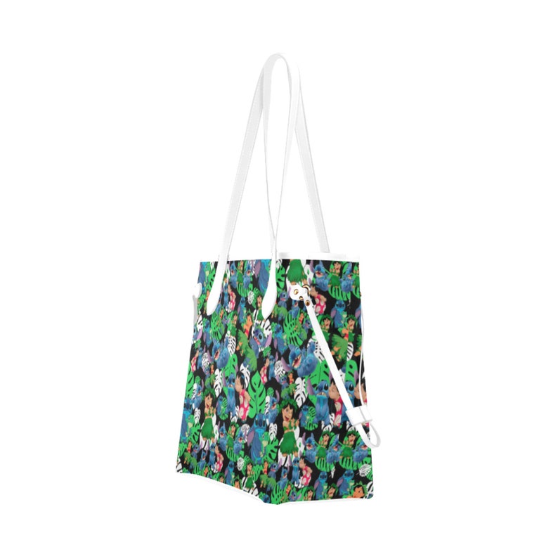 May include: A white tote bag with a colorful print of cartoon characters and tropical leaves. The print features blue, green, pink, and yellow colors.