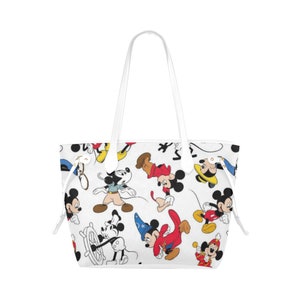 Puede incluir: Bolso tote blanco con un patr&oacute;n de Mickey Mouse en varias poses y atuendos. El bolso tiene asas de cuero blanco y un cierre de cord&oacute;n.