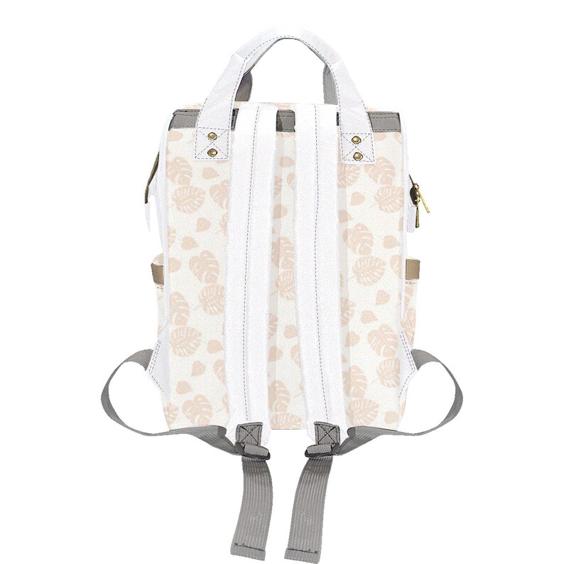 Puede incluir: Una mochila de lona blanca con un estampado floral rosa. La mochila tiene correas ajustables y un asa superior.