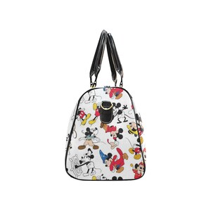 Puede incluir: Bolso de viaje blanco con un patr&oacute;n repetido de Mickey Mouse en varias poses. El bolso tiene asas y ribetes negros, con herrajes dorados. El bolso est&aacute; dise&ntilde;ado para viajar y tiene una est&eacute;tica cl&aacute;sica inspirada en dibujos animados.