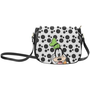 Peut inclure: Sac à bandoulière noir et blanc à pois avec une image de dessin animé de Dingo. Dingo porte un chapeau vert et a une expression surprise.