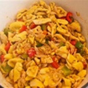 May include: A white bowl filled with a yellow and red dish. The dish contains diced red peppers, green peppers, and yellow noodles.