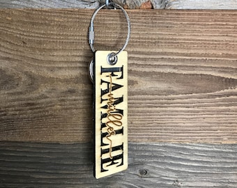 May include: A wooden keychain with the word "FAMILY" and the name "Miller" written in cursive. The keychain is attached to a silver metal chain.