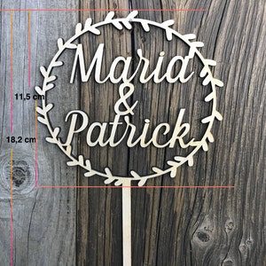May include: Wooden cake topper with a wreath design and the names "Marid & Patrick" in cursive lettering. The topper is 18.2 inches tall and 11.5 inches wide.