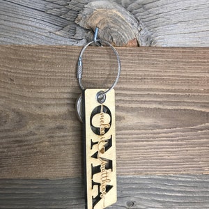 May include: Wooden keychain with the name "Olivia" and the text "Melanie & Matthias" with a heart symbol.