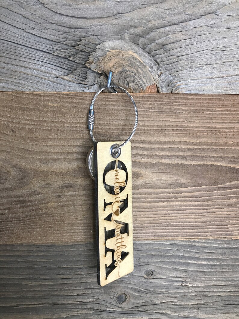May include: Wooden keychain with the name "Olivia" and the text "Melanie & Matthias" with a heart symbol.