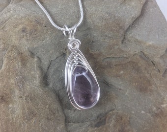 May include: A silver chain necklace with a pendant featuring a purple gemstone wrapped in silver wire.
