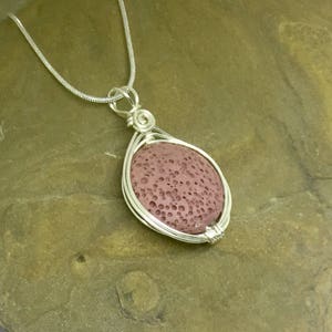 May include: A silver chain necklace with a pendant featuring a round, reddish-brown lava rock wrapped in silver wire.