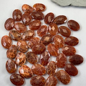 May include: A collection of 25 brown agate gemstone beads with a unique, patterned surface. The beads are oval shaped and have a polished, faceted finish.