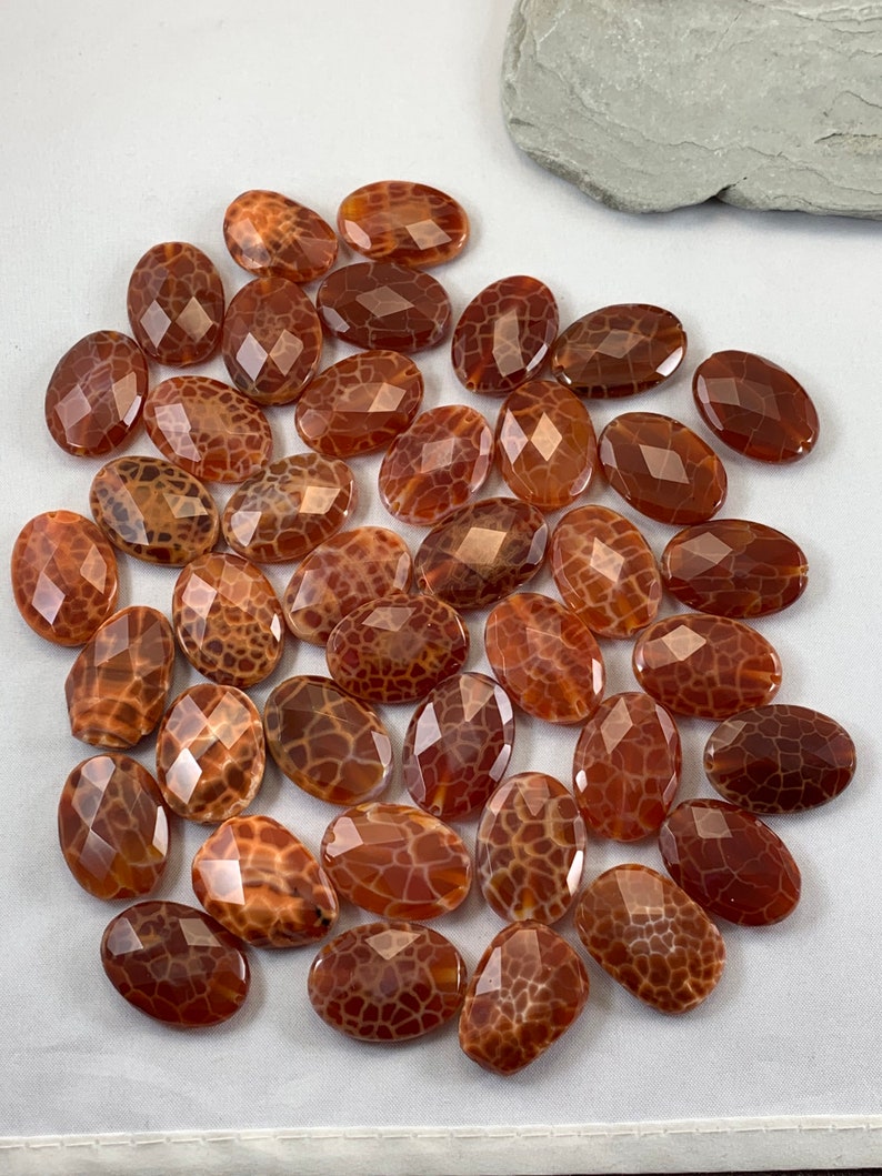 May include: A collection of 25 brown agate gemstone beads with a unique, patterned surface. The beads are oval shaped and have a polished, faceted finish.
