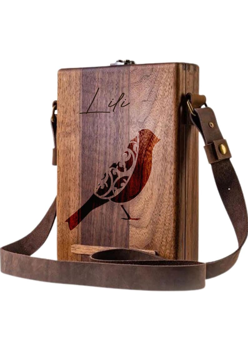 May include: A wooden box with a brown leather strap and a bird design. The box is engraved with the name "Lifi".