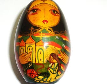 Hand painted wooden egg. Hand turned and hand painted story egg. 2.5" tall. Depicts a sad lady, a village and church dear to her