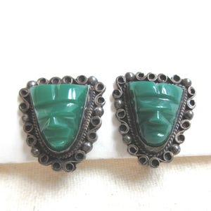 1950s Mexican sterling silver screw back earrings with carved green stone mask image. Marked RPH 925 are 1&quot; tall.