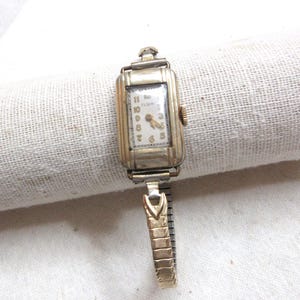 Sometimes working ladies Elgin mechanical wind up wrist watch.  Size 6.5&quot; wrist. Back is marked R Base Metal. Has a Speidel stretch band