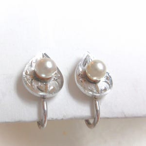 Sterling silver screw back earrings with genuine pearls set in the center of a silver leaf. 3/8" long. Good used condition