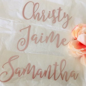 May include: Three names, Christy, Jaime, and Samantha, are written in a cursive script on a white background. The names are written in a rose gold color.