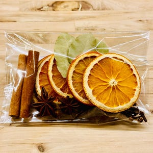 Puede incluir: Una bolsa de plástico transparente llena de rodajas de naranja secas, palitos de canela, anís estrellado y hojas de laurel. Estos ingredientes se utilizan a menudo para potpourri o para hervir a fuego lento en la estufa para crear un aroma festivo.