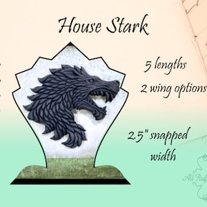 May include: A black and white direwolf head, the sigil of House Stark, is displayed on a white and green stand. The stand is 16 inches tall and has a 2.5 inch snapped width. The direwolf is available in 5 lengths and 2 wing options.