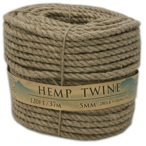 May include: A tightly wound coil of natural hemp twine. The label reads "HEMP TWINE" with measurements of 120 feet and 5mm thickness, and a strength of 280 pounds. The twine is a light brown color.