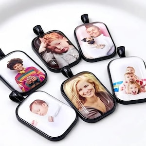 May include: Six rectangular pendants with black metal frames and bails, each featuring a unique color photograph under a clear glass dome. The images display various portraits of individuals and children, showcasing diverse expressions and clothing styles.