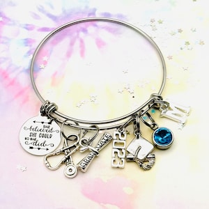 A stainless steel nurse graduate charm bracelet that is available in 3 sizes. This gift will arrive with the following charms, She believed she could so she did, stethoscope, diploma, 2023, grad cap, and your choice of initial and birthstone.