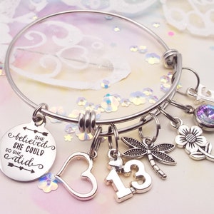 A 13th birthday charm bracelet with the following charms included, she believed she could so she did, an open heart, the #13, a dragonfly, a flower, and the initial and birthstone of your choice. Silver finish and comes in 3 sizes, small medium large