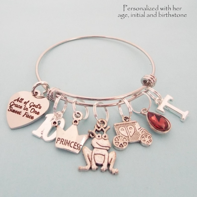 This charm bracelet has a silver finish and is available in three sizes. It will arrive with the following charms, All God's grace in one sweet face, the number 10, princess crown, frog, princess coach, your choice of initial and birthstone.