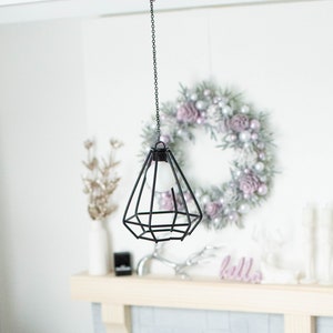 May include: A miniature dollhouse living room with a white fireplace, a white couch, a white coffee table, a white Christmas tree, a white mug with the text "Coffee Mother", a white wreath with silver and pink ornaments, and a black hanging light fixture.