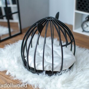 May include: Black wire cage pet bed with a white cushion. The bed is on a white fluffy rug.