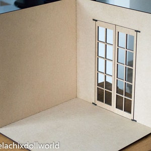 May include: A miniature room with a brown cardboard floor and walls. The room has a single window with two French doors, each with 9 panes of glass.