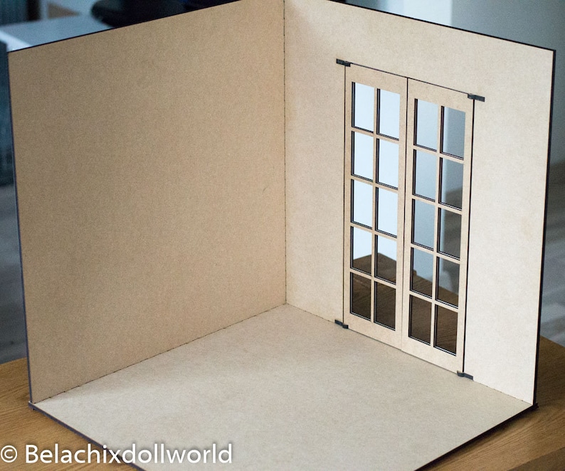 May include: A miniature room with a brown cardboard floor and walls. The room has a single window with two French doors, each with 9 panes of glass.