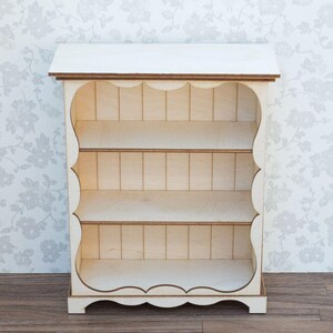 Pu&ograve; includere: Libreria in legno bianco con tre ripiani e un bordo a festoni. La libreria &egrave; in legno e ha una finitura bianca.