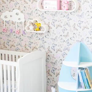 May include: A white crib with a white and gray patterned mattress, a white cloud-shaped shelf with a pink number 3 and a light box that says "Sweet Dreams", a white cloud-shaped shelf with a yellow giraffe toy, a blue rocket-shaped bookshelf with books, and a white rocking horse.