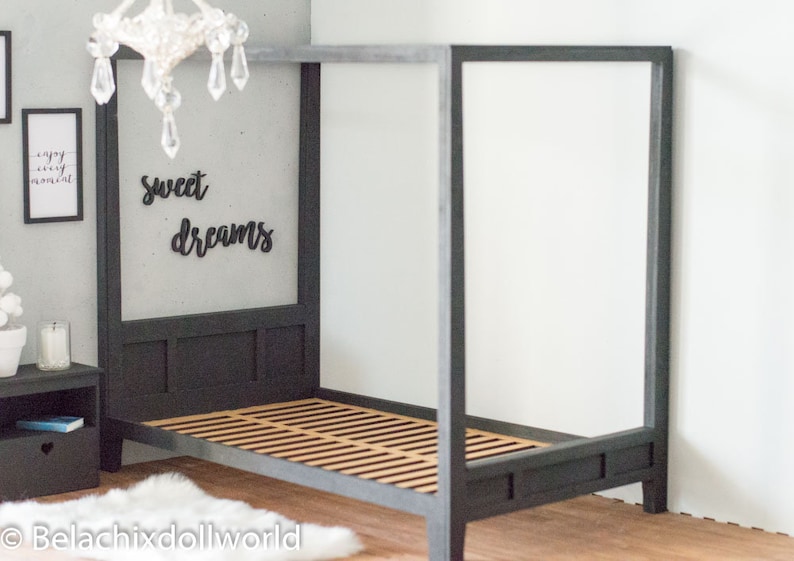 Puede incluir: Una cama con dosel negro con una cabecera y un piecero de madera con listones. La cabecera tiene una pared gris detr&aacute;s con las palabras "sweet dreams" escritas en negro.