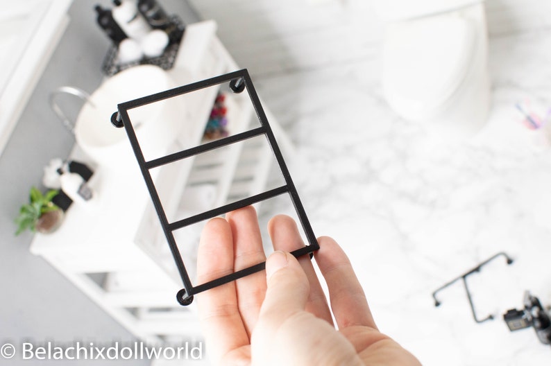 May include: Black metal shelf unit with three tiers. The shelf unit is designed for dollhouse decor.