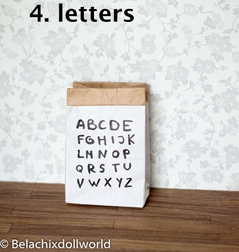 May include: A brown paper bag with the alphabet printed on it in black ink. The bag is sitting on a wooden floor with a floral wallpaper in the background. The text on the bag reads "4. letters".