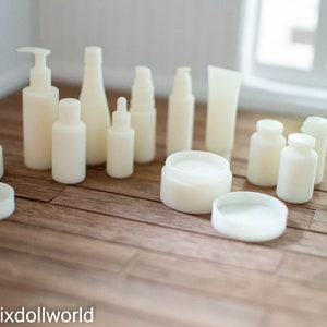 May include: A collection of white plastic bottles and jars, some with pumps, caps, and lids, arranged on a wooden surface.