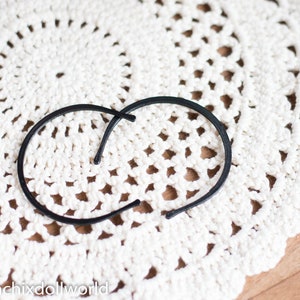 May include: Two black plastic hair clips on a white crocheted doily.