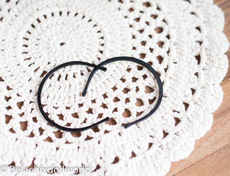 May include: Two black plastic hair clips on a white crocheted doily.
