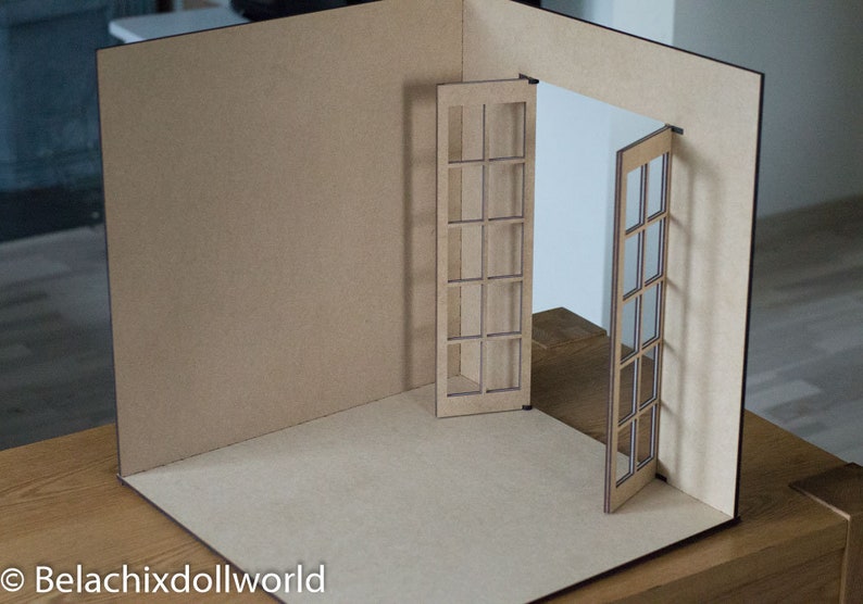 May include: A miniature dollhouse room with brown cardboard walls and a set of double French doors with glass panes.
