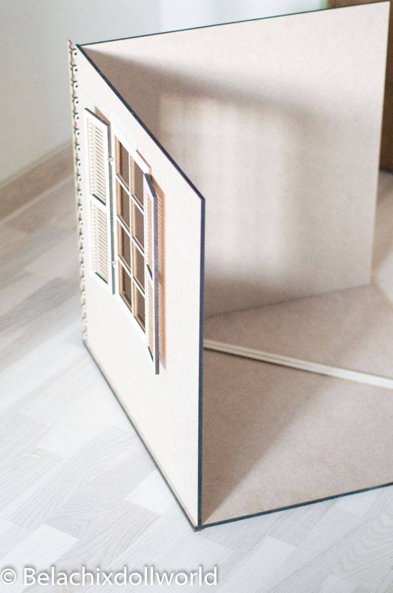 May include: A white dollhouse room with a window and shutters. The room is made of wood and has a light brown floor.