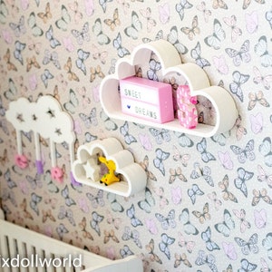 May include: White cloud-shaped shelves with a pink light-up sign that says "Sweet Dreams" and a pink letter "S" on a wall with a butterfly pattern.