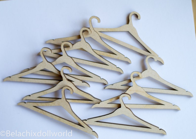 May include: A set of ten wooden hangers, all in the same style, with a simple, rounded design. The hangers are arranged in a pile, with the hooks facing up.