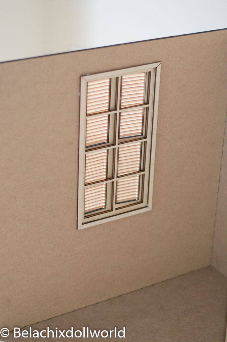 May include: A miniature wooden window with a light brown frame and a grid of six panes. The window has a light brown wood slat blind inside.