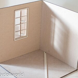 May include: A cardboard room with a single window, a light brown color, and a shadow on the wall. The room is empty except for two white sticks in the corner.