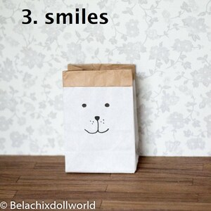 May include: A white paper bag with a brown top and a black and white cartoon bear face with a smile. The text "3. smiles" is above the bag.