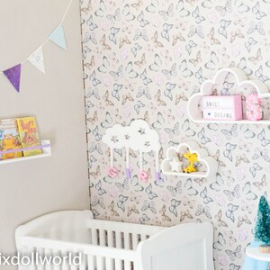 May include: A white crib with a white cloud-shaped shelf with the text "Sweet Dreams" and a pink number 5. The shelf is on a wall with a butterfly pattern wallpaper. There are also two other white cloud-shaped shelves with a star and a yellow giraffe toy.
