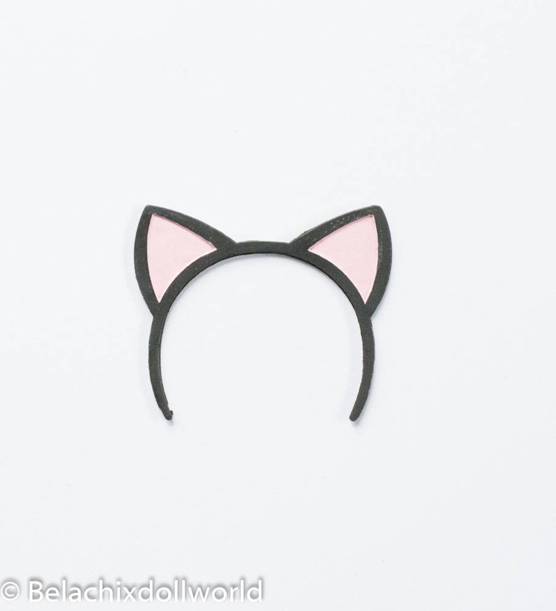 May include: A black headband with pink cat ears. The ears are outlined in black and have a pink interior. The headband is designed to be worn on the head and is a cute accessory.